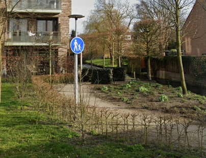 foto van voetpad langs een sloot met voetgangersbord.